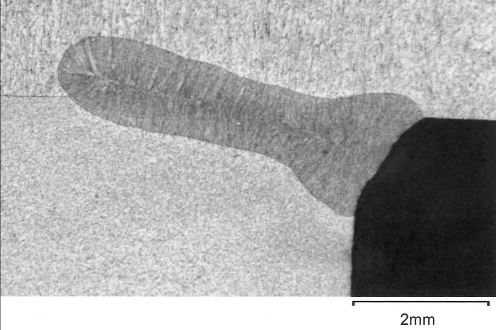 Cross section image of a laser weld. Microscopic view of a segmented, elongated structure about 2 millimeters long on a textured surface