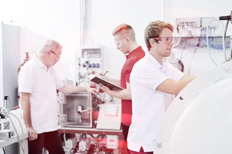 Three persons in a leak testing lab